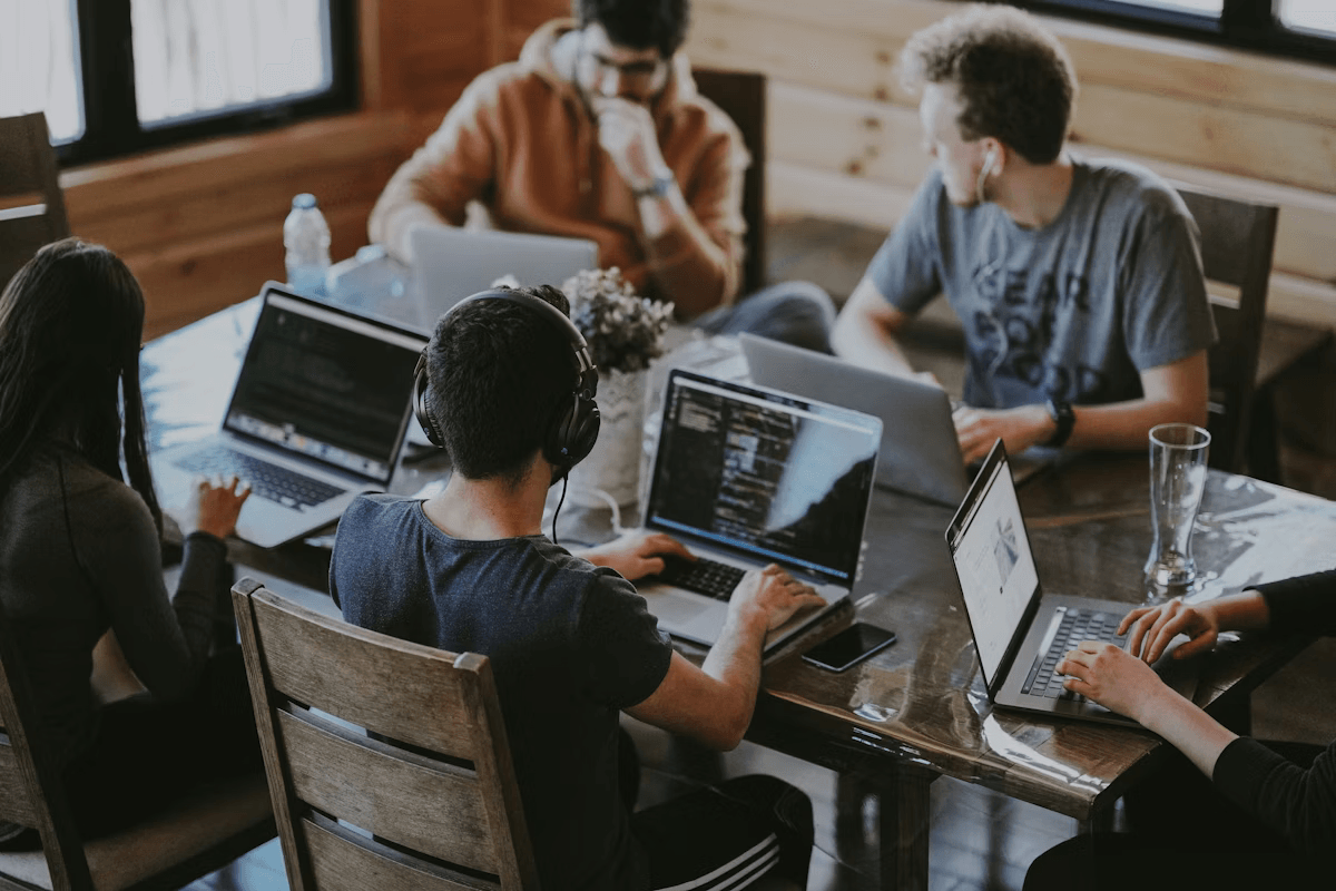 Startup product team collaborating around a table with laptops and notes